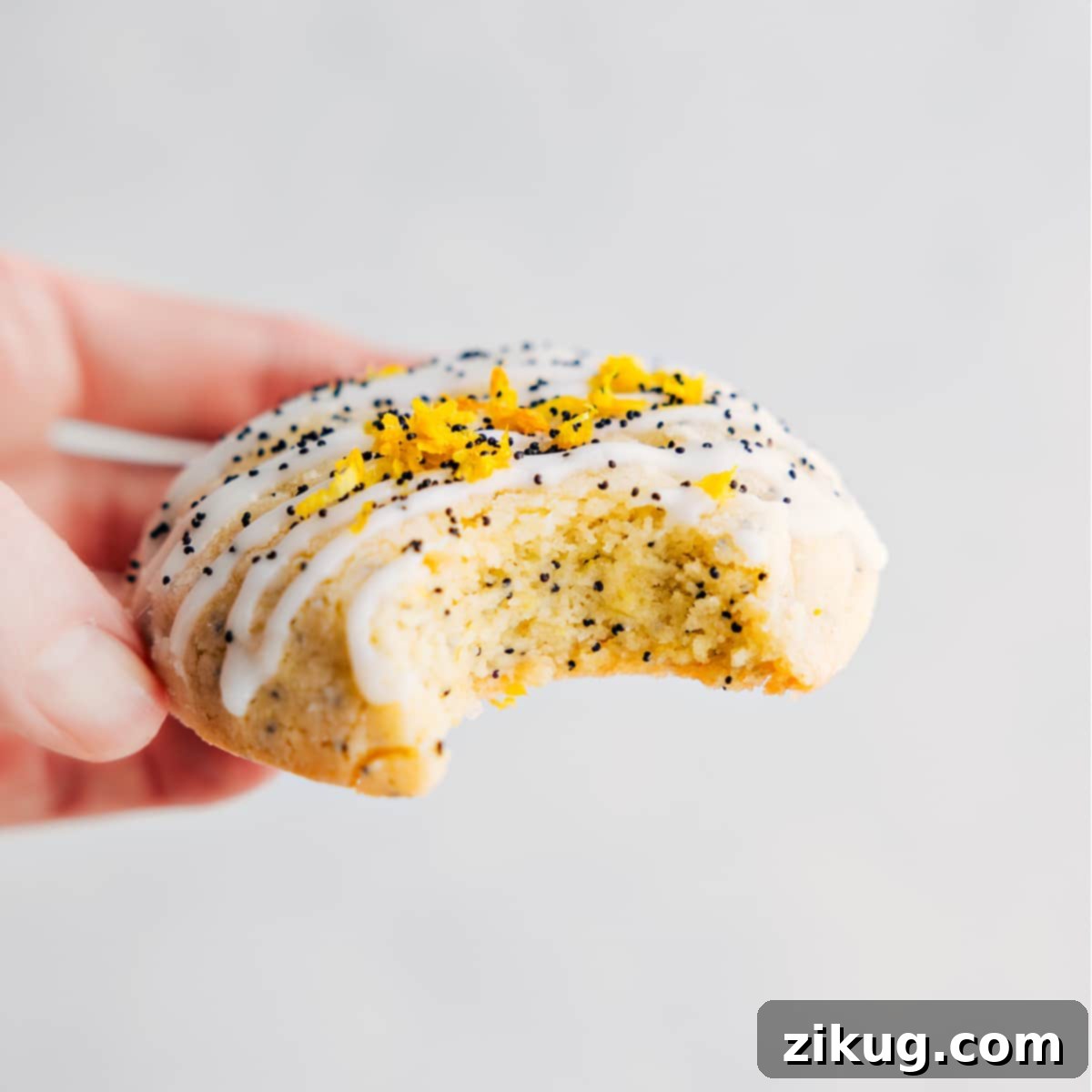 Irresistible Lemon Poppy Seed Cookie Dessert A delicious Lemon Poppy Seed Cookie, topped with a glistening lemon glaze and fresh lemon zest, with a perfect bite taken out, revealing its soft and chewy interior.