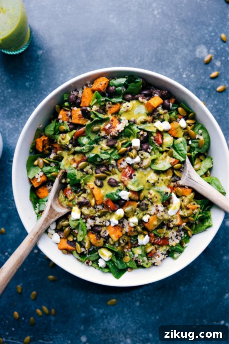 This Quinoa Salad Recipe is our new favorite! Roasted sweet potato, sweet pepper, and black beans atop a bed of spinach and cooked quinoa with roasted pumpkin seeds and crumbly soft cheese. Add the show-stopping basil-lime vinaigrette and we're ready to eat! Recipe via ChelseasMessyApron #dinner #quick #easy #simple #best #fresh #clean #cleaneating #detox #detoxsalad #goatcheese #dressing #quinoa #salad #recipe Overhead image of the Quinoa Salad Recipe, showcasing roasted sweet potato, red bell pepper, black beans, spinach, quinoa, pumpkin seeds, and cheese.