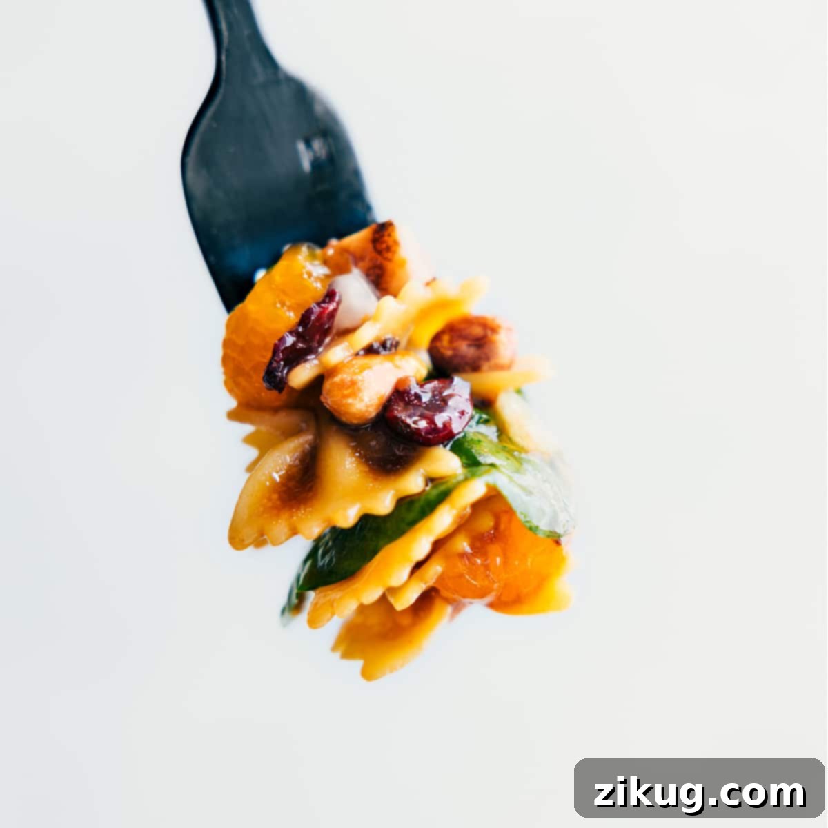Easy And Delicious Teriyaki Chicken Salad Recipe A forkful of Teriyaki Chicken Salad showcasing all the delicious components: pasta, chicken, spinach, oranges, and nuts, ready to be enjoyed.