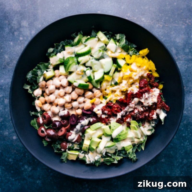 This Tahini Dressing is luxuriously thick and creamy without any mayo or cream! It's delightfully flavored with a hint of lemon and touch of honey. Recipe via chelseasmessyapron #salad #saladdressing #tahini #dressing Overhead image of a vibrant, dressed salad generously topped with homemade Tahini Dressing, showcasing the rich texture and appealing presentation.