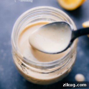 Creamy Tahini Dressing 2 A bowl of creamy Tahini Dressing garnished with fresh herbs, showcasing its rich texture and appetizing appearance.