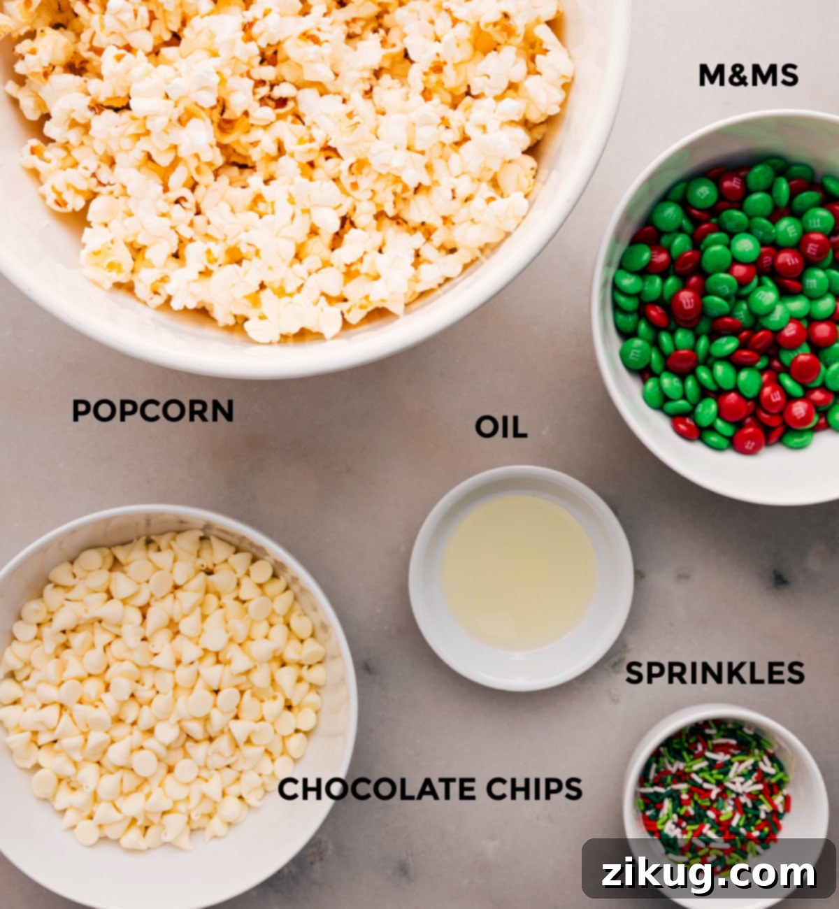 Essential Ingredients for Festive Christmas Popcorn A colorful array of ingredients for Christmas Popcorn including red and green M&M's, white chocolate chips, popcorn, and sprinkles.