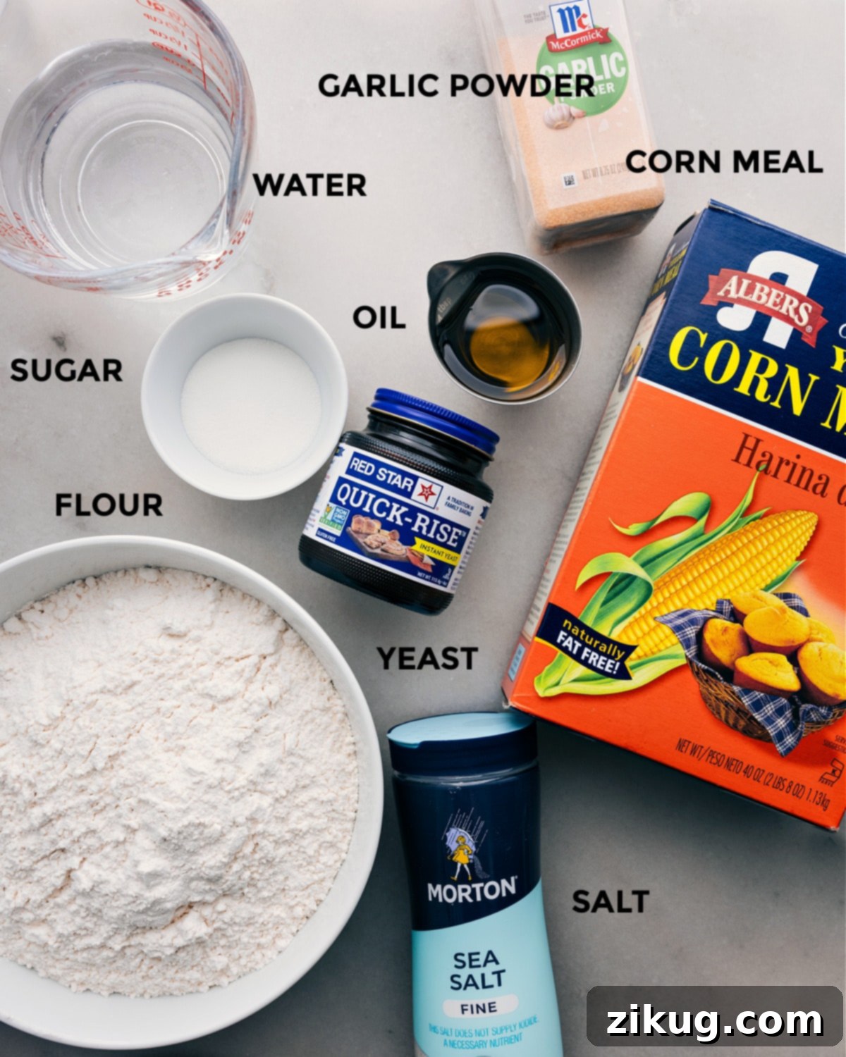 Essential Ingredients for Easy Pizza Dough A collection of essential ingredients for homemade pizza dough, including flour, yeast, sugar, salt, olive oil, and water, laid out on a kitchen counter.