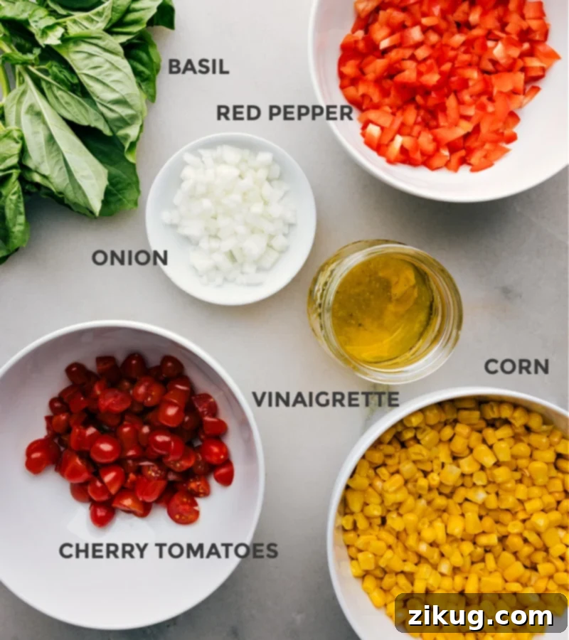 Corn and Tomato Salad recipe features a vibrant blend of sweet, juicy corn and tomatoes balanced by the crunch of diced bell pepper and onion. The tangy lime vinaigrette, spiked with a hint of maple syrup and Dijon mustard, adds a burst of citrusy freshness that ties together everything beautifully! Recipe via chelseasmessyapron #sidedish #best #quick #easy #simple #summer #summersalad #corn #tomato #salad A vibrant selection of fresh ingredients for Corn and Tomato Salad laid out on a white surface, including bright yellow corn kernels, red cherry tomatoes, diced red bell pepper, sliced red onion, and fresh basil leaves.