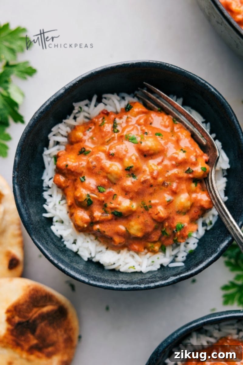 Delicious Butter Chickpeas served with rice and naan. Overhead view of a vibrant bowl of Butter Chickpeas, garnished with fresh herbs, served alongside fluffy basmati rice and warm naan bread.