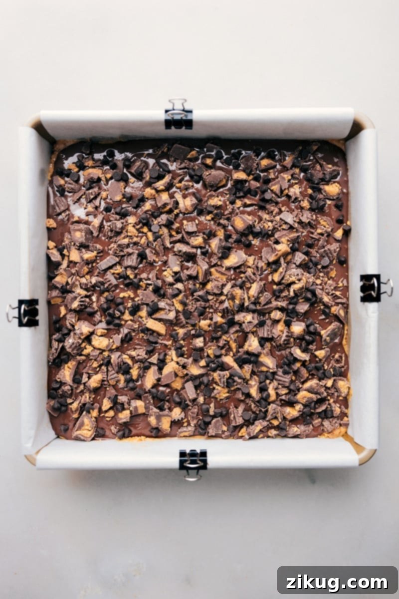 Sweet and Salty Peanut Butter Pretzel Bars 8 Overhead image of freshly made Pretzel Peanut Butter Bars, still in the pan, topped with peanut butter cups and chocolate chips, ready to be enjoyed.
