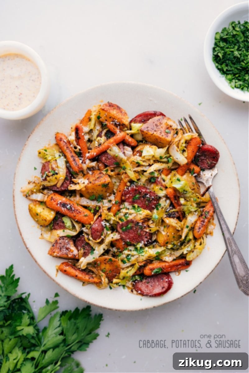 One-Pan Cabbage, Potatoes, and Sausage: A hearty and flavorful dish featuring smoky sausage, roasted potatoes, and tender cabbage, all topped with a rich Dijonnaise and Parmesan. Overhead shot of the finished One-Pan Cabbage, Potatoes, and Sausage dish, beautifully garnished with fresh parsley and a generous drizzle of creamy Dijonnaise sauce.