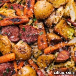 Close-up of One-Pan Cabbage, Potatoes, and Sausage dish, perfectly roasted and ready to eat, with a creamy Dijonnaise sauce drizzled over it and fresh parsley garnish.