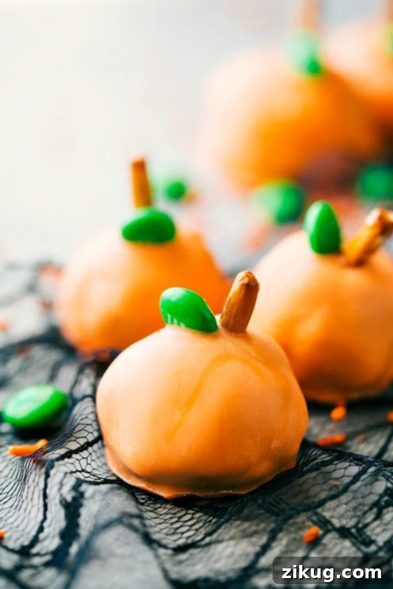 Spooktacular Oreo Truffles 4 Festive orange pumpkin Oreo balls decorated with green M&M's and pretzel stems, perfect for a fall or Halloween celebration.