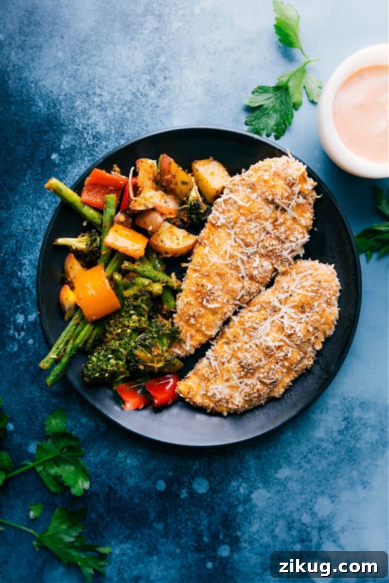 The Best Baked Parmesan Chicken Tenders and Roasted Veggies Crispy Baked Parmesan Chicken Tenders served on a plate alongside perfectly roasted broccoli, potatoes, and bell peppers, ready to be enjoyed.