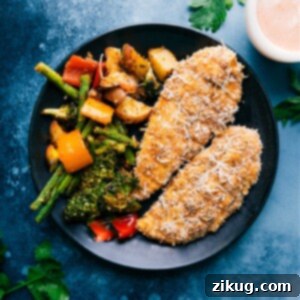 Crispy Baked Parmesan Chicken Tenders served with roasted vegetables on a plate.