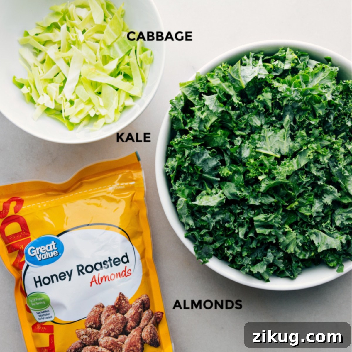 Ingredients In Chick-Fil-A Kale Salad All the core ingredients for Chick-fil-A Kale Salad copycat, including fresh kale with its vibrant green leaves, crisp thinly sliced cabbage, and a generous portion of crunchy almonds, neatly prepped and laid out for easy assembly and preparation.