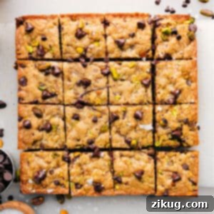 Close-up of freshly baked blondies with chocolate chips and nuts, cut into squares.