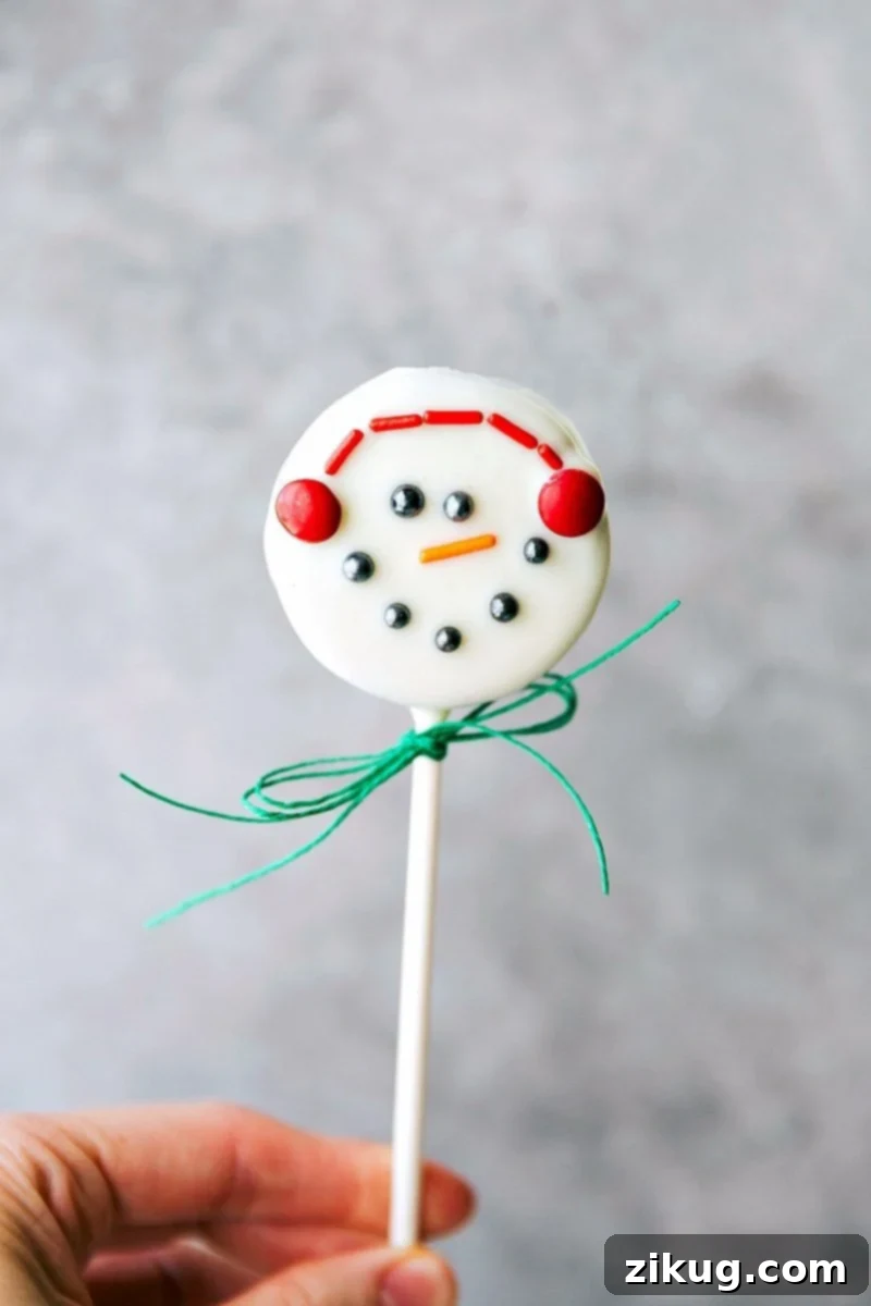 Delicious snowman Oreo pops perfect for Holiday celebrations. Close-up image of the adorable snowman Oreo pop with earmuffs and a carrot nose.