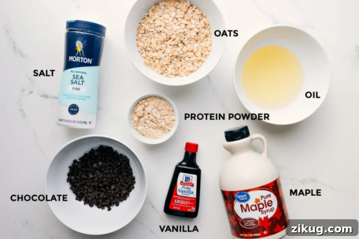 Essential Ingredients for Protein Cookie Dough A collection of fresh ingredients laid out for protein cookie dough: oats, coconut oil, salt, vanilla protein powder, maple syrup, vanilla extract, and chocolate chips.