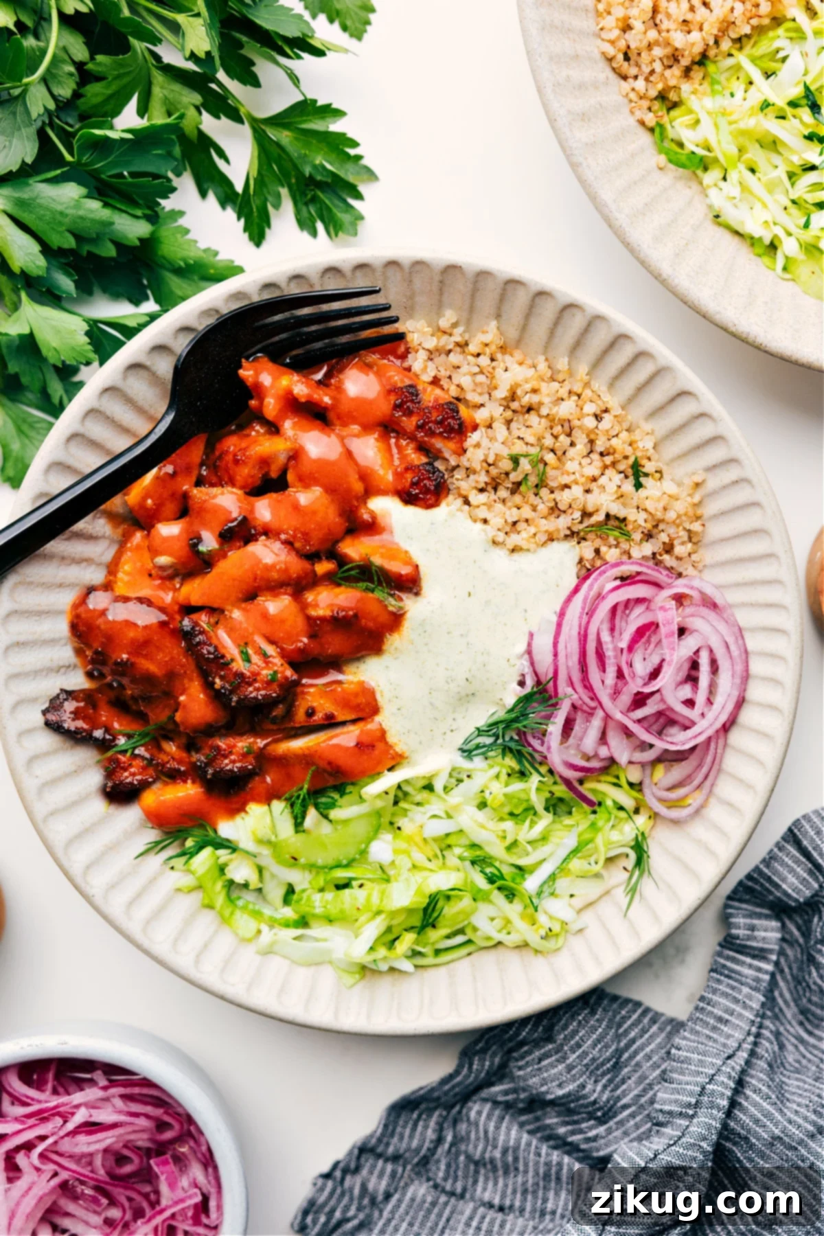 Flavorful and Delicious Buffalo Chicken Bowl Recipe A vibrant Buffalo Chicken Bowl served over fluffy quinoa, generously topped with a crunchy slaw, bright pickled red onions, and a creamy Green Goddess sauce, inviting you to savor every delicious layer.