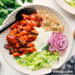 A close-up shot of a Buffalo Chicken Bowl, featuring crispy buffalo chicken, fresh slaw, and a creamy drizzle, all layered over a base of quinoa.