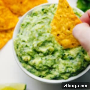 The best creamy and fresh guacamole recipe in a bowl, garnished with a lime wedge and ready to be served.