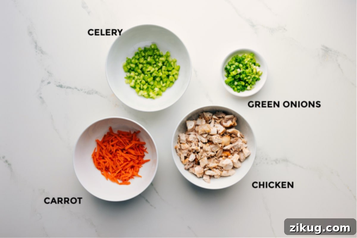 Ingredients In Hot Honey Chicken Salad Ingredients prepped out for easy assembly including celery, carrot, green onions, and chopped chicken.