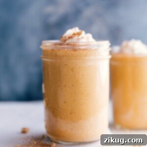 A cup filled with a creamy pumpkin protein shake, topped with a swirl of whipped cream and a sprinkle of spices.