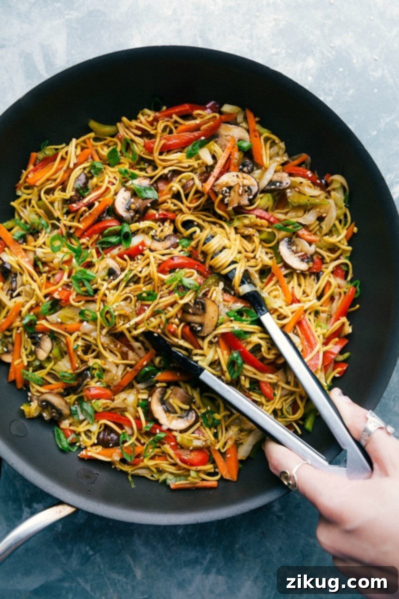 A vibrant bowl of freshly prepared vegetarian Chow Mein, ready to be served, showcasing a generous mix of colorful vegetables and glistening noodles coated in a rich, savory sauce.