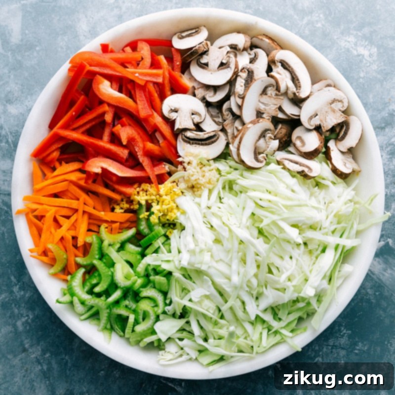 A neatly arranged bowl of freshly chopped vegetables including shredded cabbage, julienned carrots, sliced bell peppers, and mushrooms, prepared and ready to be added to the Chow Mein stir-fry.