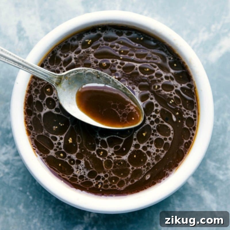 A small bowl filled with a rich, dark, and glossy homemade sauce, perfectly prepared to be poured over the stir-fried noodles and vegetables in the Chow Mein recipe.