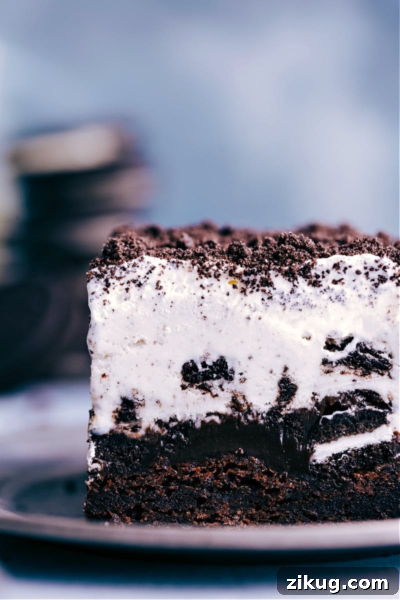 A delicious slice of Brownie Oreo Ice Cream Cake, perfectly layered and ready to satisfy your sweet cravings. An up-close, tempting image of a perfectly cut slice of Brownie Oreo Ice Cream Cake, ready to be enjoyed, showing off its beautiful layers.