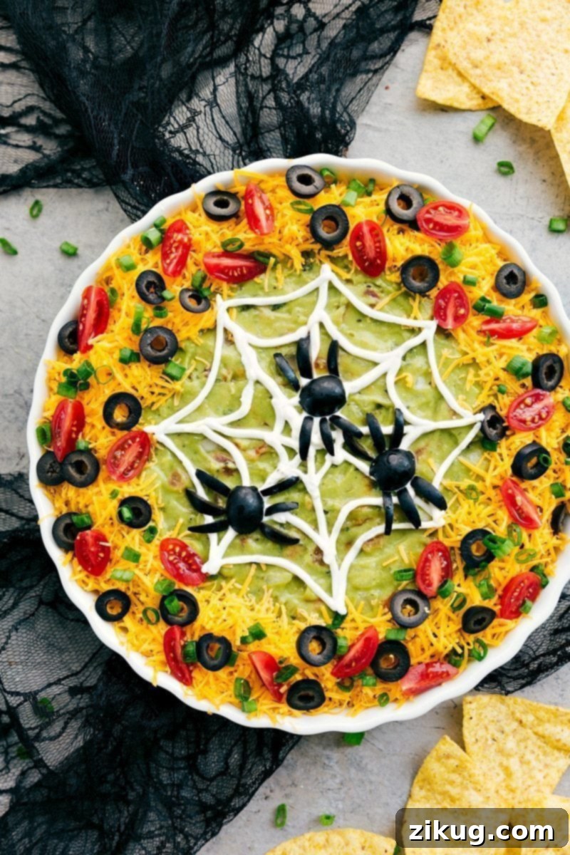 Spider Web: Four easy, & creative Halloween appetizer ideas that are so delicious -- Spider Web 7-Layer Dip, Walking Dead Mummy Dogs, Monster Meatball Sliders, & Cheesy Monster Fingernail Bread. chelseasmessyapron.com #halloween #appetizers #spiderweb #spooky #dip #seven #layer #olives #guacamole Image of the spider web 7-layer dip, a perfect easy Halloween appetizer