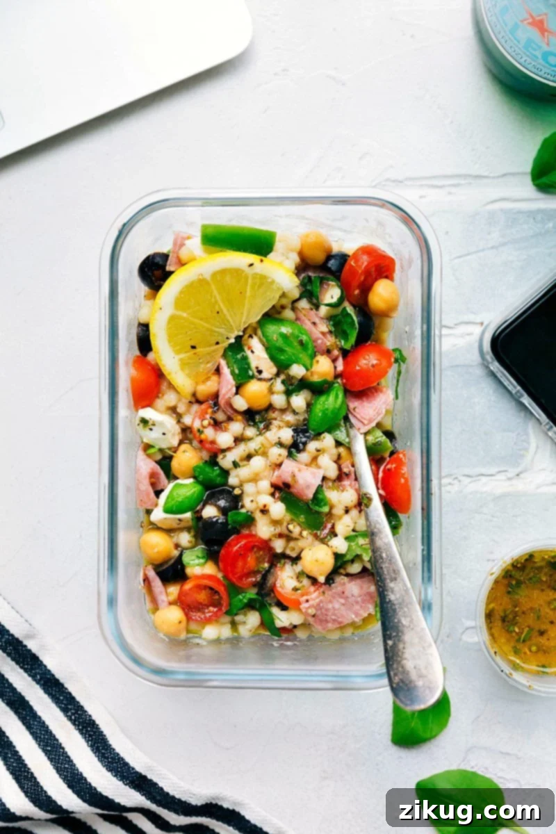 Overhead shot of the completed Italian Couscous Salad in a large, rustic bowl, garnished beautifully with fresh basil leaves.