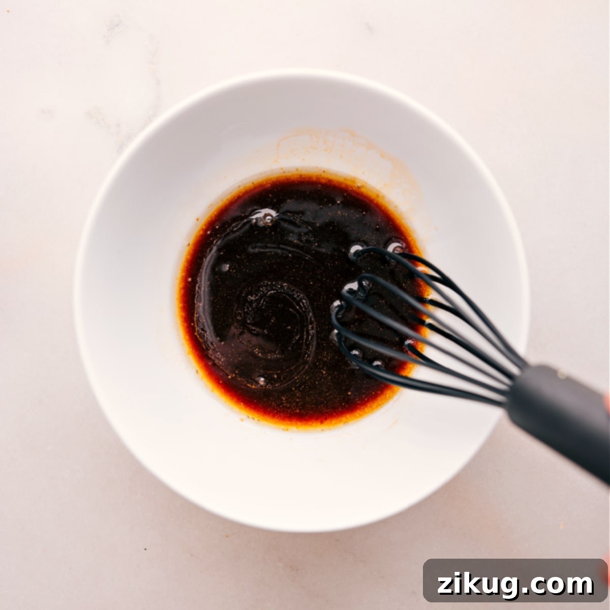 Whisk Together Homemade Stir Fry Sauce for Ground Turkey Hands whisking together the homemade stir-fry sauce in a small bowl, showcasing the blend of soy sauce, sesame oil, Sriracha, and brown sugar for the ground turkey stir fry. The ingredients are perfectly combined to create a rich, savory, and slightly sweet sauce.