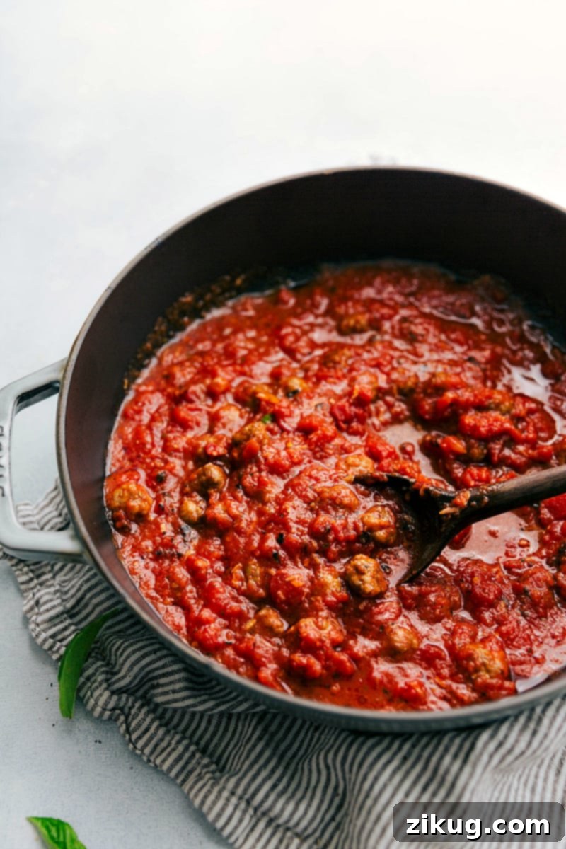 Hearty Sausage Gnocchi 4 Close-up of golden brown sausage meatballs simmering in a rich red tomato sauce.