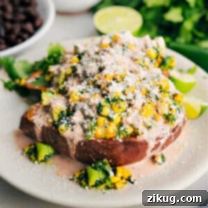 A vibrant, fully assembled loaded sweet potato with Mexican street corn topping, sauce, and cotija cheese.