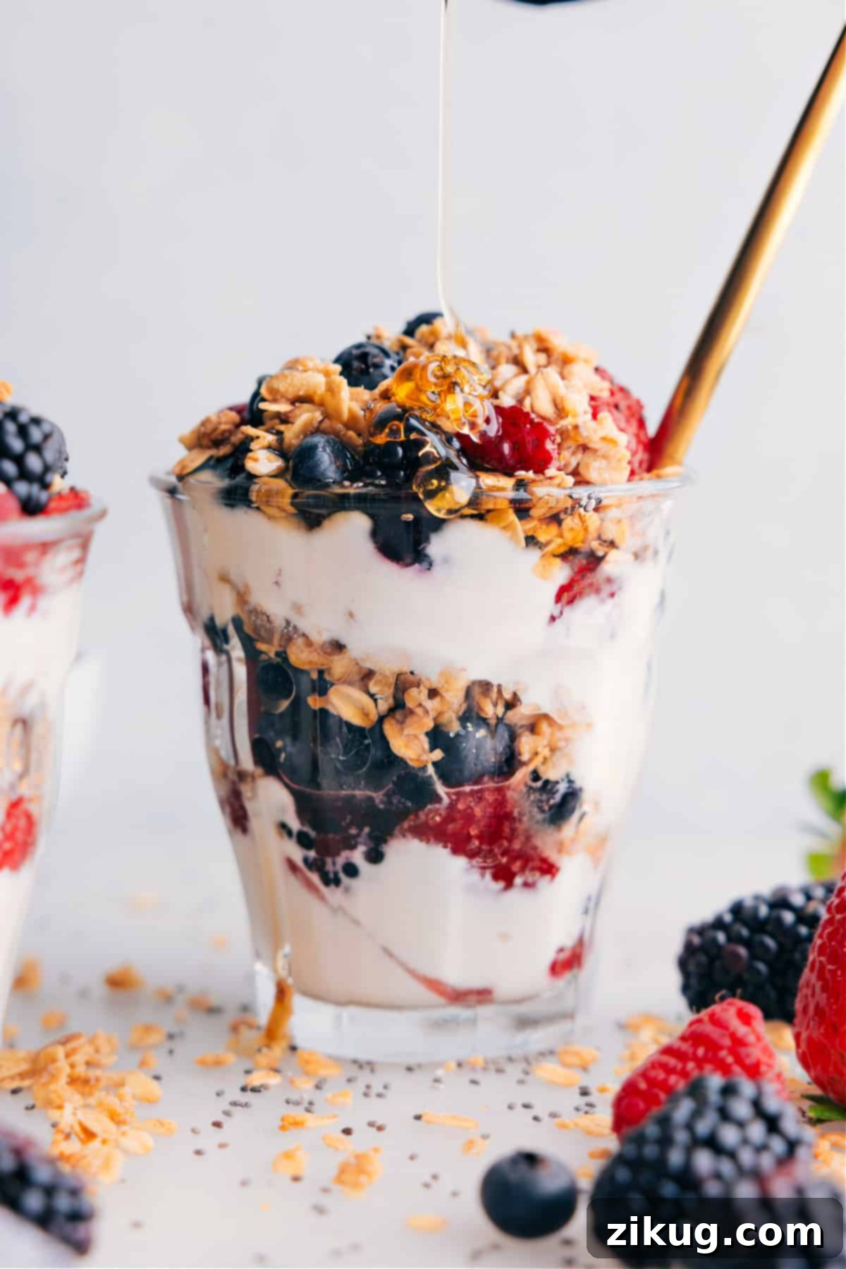 Drizzling Honey on Yogurt Parfait A yogurt parfait in a clear glass, with a hand drizzling golden honey over the top layer of berries and granola, enhancing its appeal and sweetness.