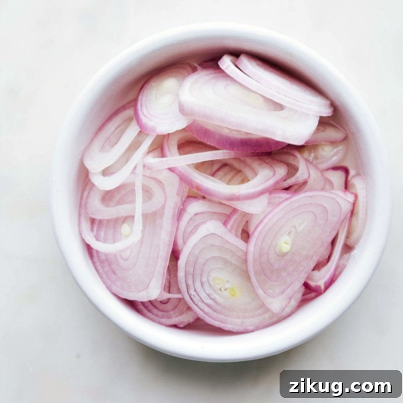 Sliced Shallots for Pickling Fresh shallots finely sliced, ready to be used as a vibrant and tangy topping for the delicious ground beef lettuce wraps.