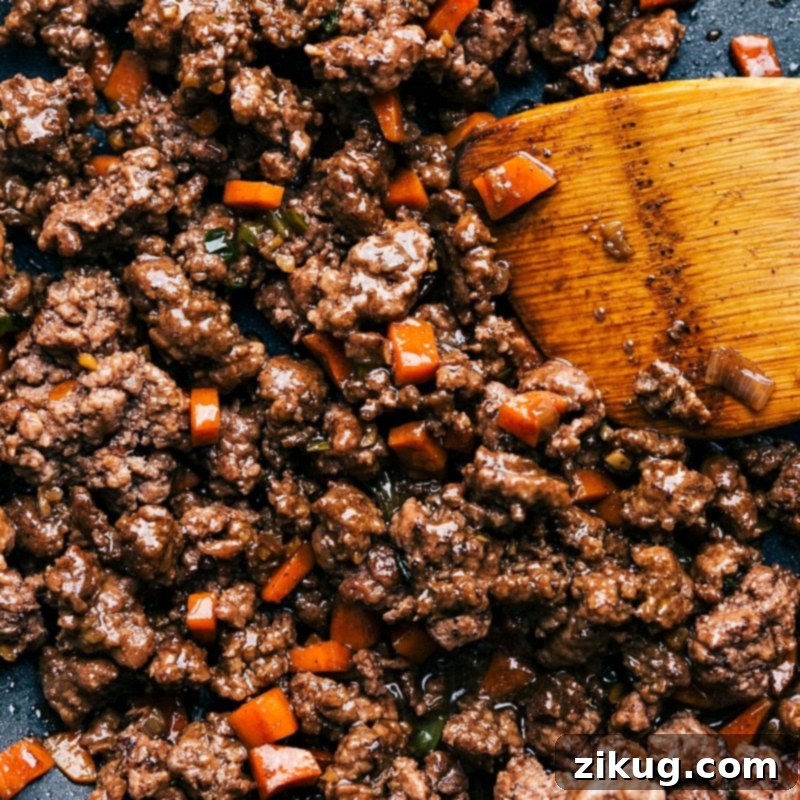 Savory Beef Lettuce Cups 3 Cooked ground beef with carrots and green onions, infused with an aromatic sauce, used in Asian-style beef lettuce wraps, ready to be wrapped in crisp lettuce leaves.