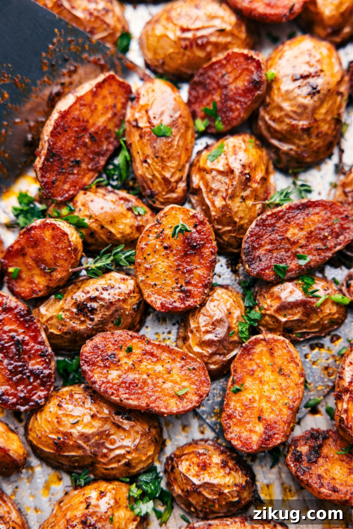The Best Crispy Roasted Potatoes Recipe Tray full of golden, crispy roasted potatoes fresh from the oven, garnished with fresh herbs.
