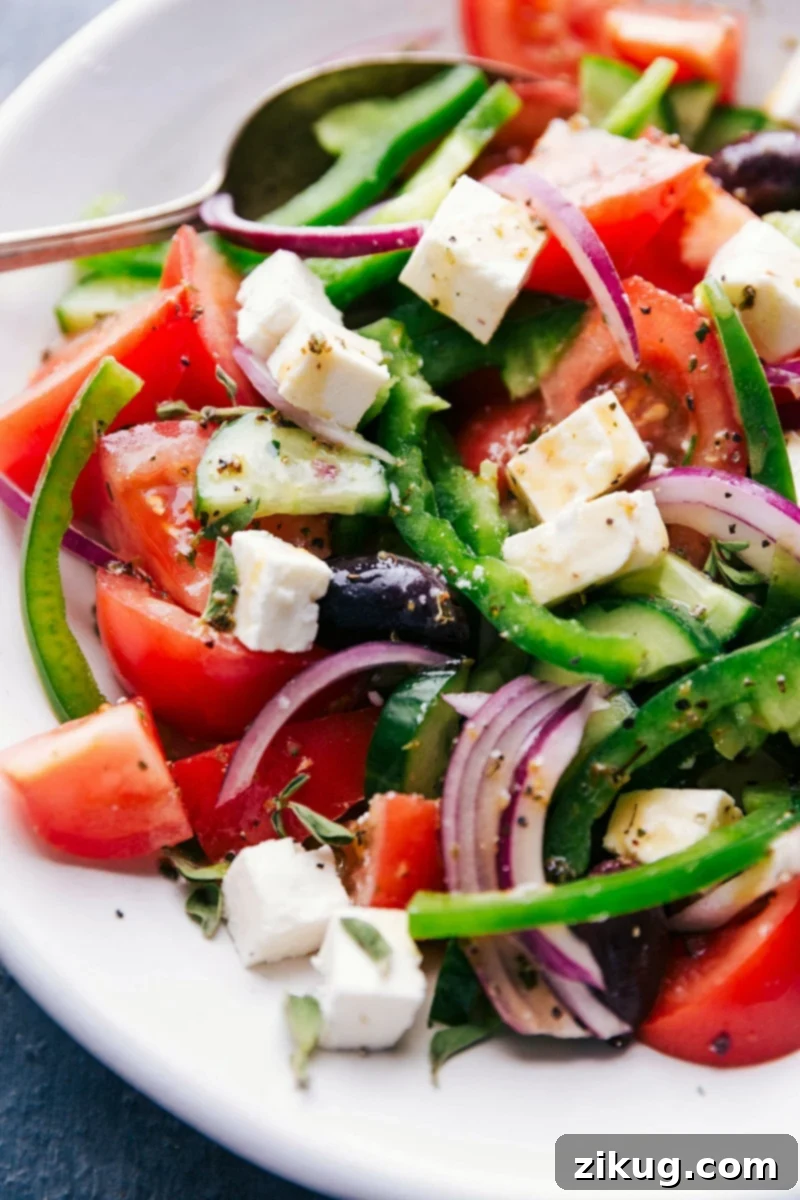 Finished Greek Salad Recipe Ready to Serve Completed greek salad recipe drizzled in dressing, ready to serve.