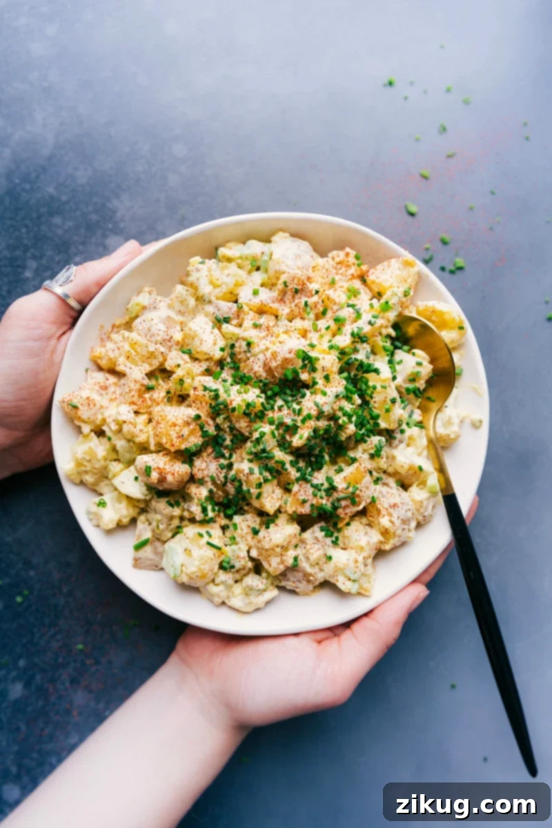 Hearty and Creamy Potato Salad with Fresh Herb Topping - A Perfect Side Dish Large bowl of creamy potato salad recipe garnished with fresh herbs, ready to be savored.