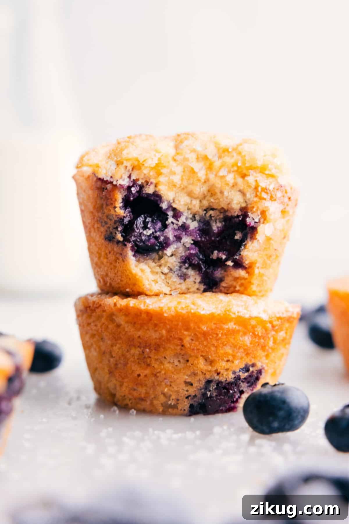 The Best Healthy Blueberry Muffins: A Wholesome Treat Stacked healthy blueberry muffins with a bite taken out of the top one, showcasing the fluffy texture and juicy blueberries.