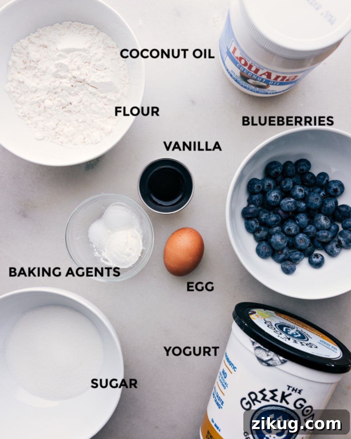 Wholesome Ingredients for Healthy Blueberry Muffins A collection of fresh, wholesome ingredients laid out for baking healthy blueberry muffins, including flour, blueberries, yogurt, and coconut oil.