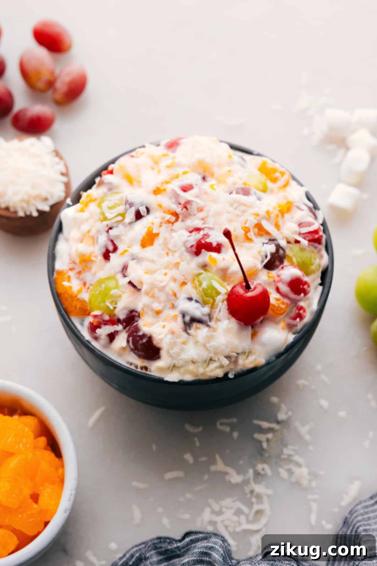 The Best Ambrosia Salad Recipe: A Festive Fruit & Marshmallow Delight A vibrant Ambrosia Salad in a decorative serving bowl, garnished with a single bright red maraschino cherry on top, highlighting its creamy texture and colorful fruit medley.