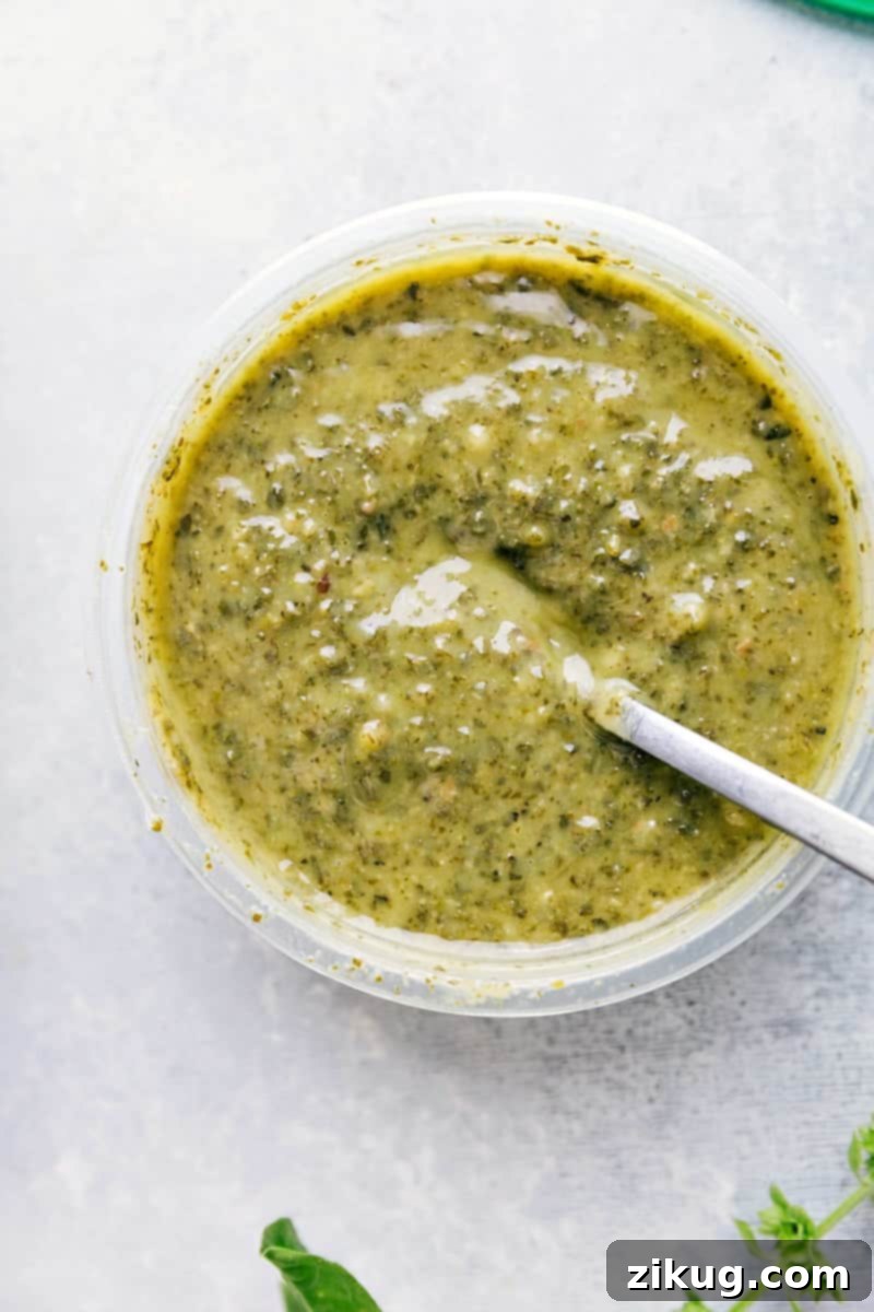 Fresh Basil Pesto: The Heart of the Dish Process shot of a vibrant green basil pesto sauce in a bowl, highlighting its freshness and rich texture, ready to be added to the pasta.