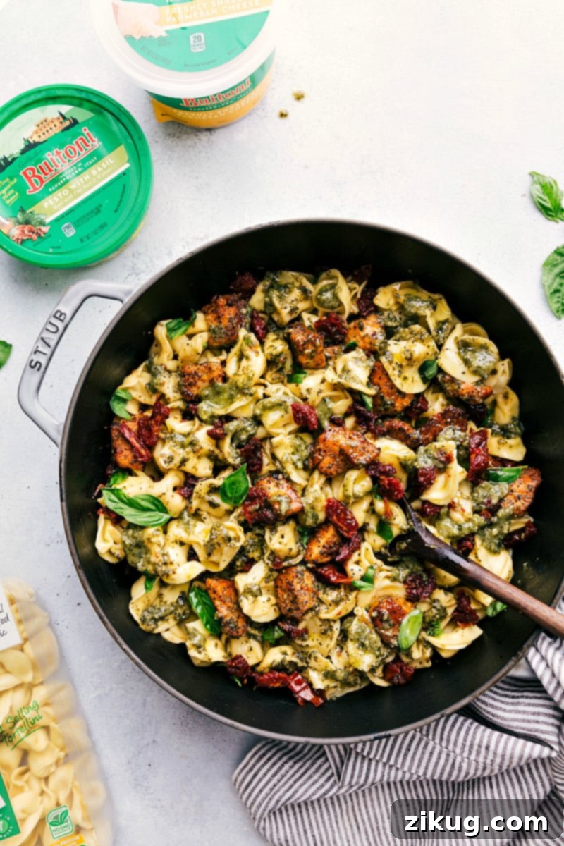 Finished One-Pot Pesto Chicken Tortellini in the Pan Overhead image of the finished Pesto Chicken Tortellini simmering in the pan, beautifully coated in pesto and garnished, ready to be served into bowls.