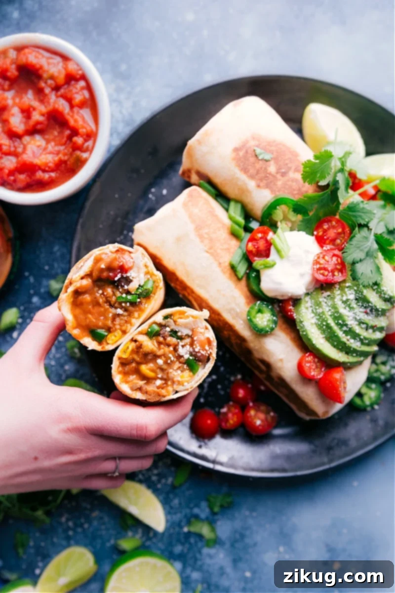 Indulge in these delicious Bean and Cheese Burritos featuring creamy, seasoned pinto beans, fluffy Mexican-spiced rice, crisp corn, savory black beans, and generous amounts of sour cream and two types of cheese. Perfectly crisped in a skillet or air fryer, these vegetarian burritos are ideal for dinner, quick meals, or meal prep. #dinner #best #quick #easy #simple #vegetarian #avocado #tomato #salsa #bean #cheese #burritos Overhead image of crispy Bean and Cheese Burritos arranged on a plate, with one expertly sliced open to reveal its vibrant, flavorful interior of creamy beans, seasoned rice, and melted cheese.