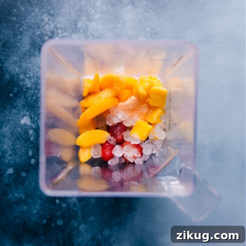 Visualize the perfect Caribbean Passion Smoothie coming to life as all ingredients, including passion fruit juice, frozen fruits, ice, and orange sherbet, are loaded into the blender. All the vibrant frozen fruits and sherbet are ready in the blender, about to be mixed into a Caribbean Passion Smoothie.