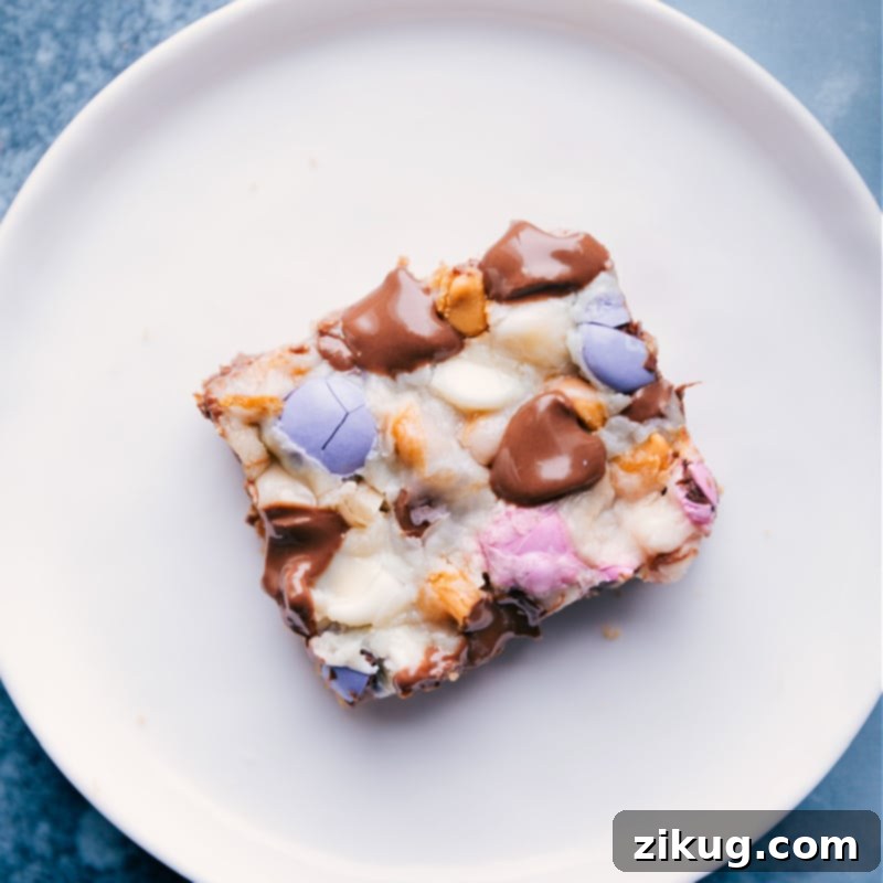 A single Magic Bar on a plate A single perfectly portioned Magic Bar resting on a white plate, showcasing its rich, multi-layered texture and delightful toppings.