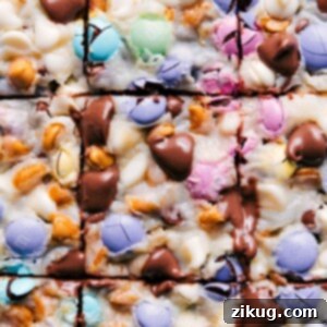 Close-up of baked Magic Bars with visible layers of graham cracker crust, chocolate, M&M's, and oats.