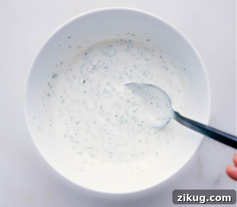 Homemade Buttermilk Ranch Dressing Recipe That Will Have You Ditching The Bottle Homemade Buttermilk Ranch Dressing Recipe in a bowl with a spoon mixing it up.