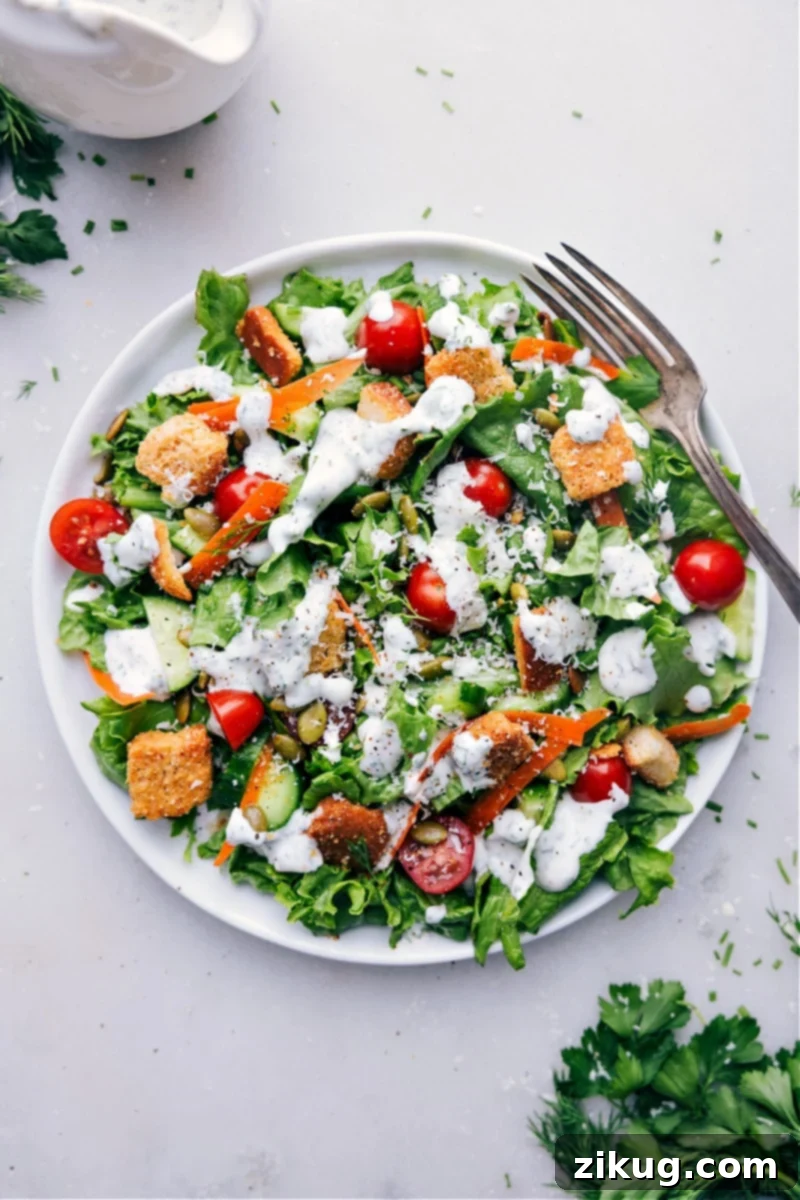 Say Goodbye To Uninspiring Store-Bought Ranch And Hello To This Incredible Homemade Ranch Dressing Recipe! Made with only the best ingredients, including the ultimate combination of fresh herbs, this dressing is a flavor explosion in every bite! Recipe via chelseasmessyapron #dip #best #quick #easy #simple #familyfriendly #kidfriendly #salad #ranch #dressing A fully dressed salad ready to be enjoyed.